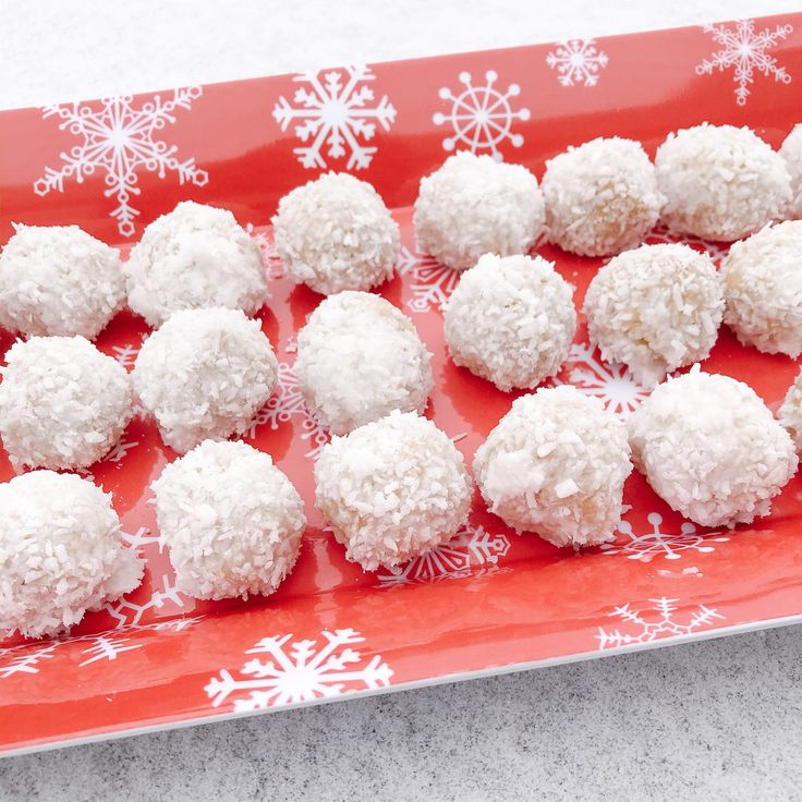 a red plate topped with snowball cookies on top of a table