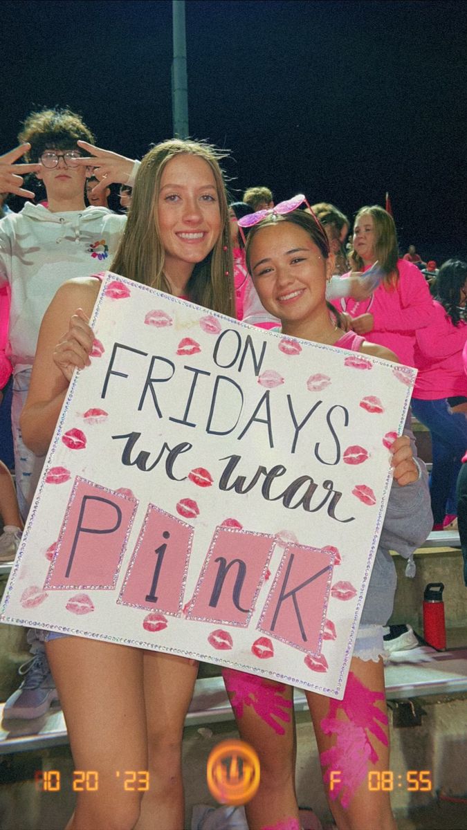 two girls holding up a sign that says pink on friday's we wear pink