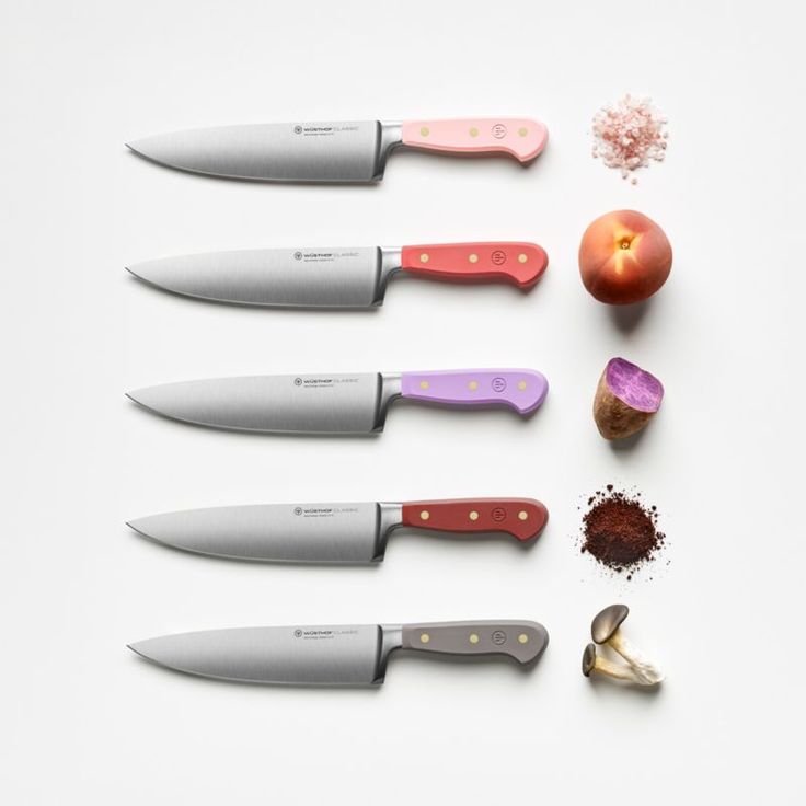 five knives are lined up next to an apple, garlic, pepper, and seasoning