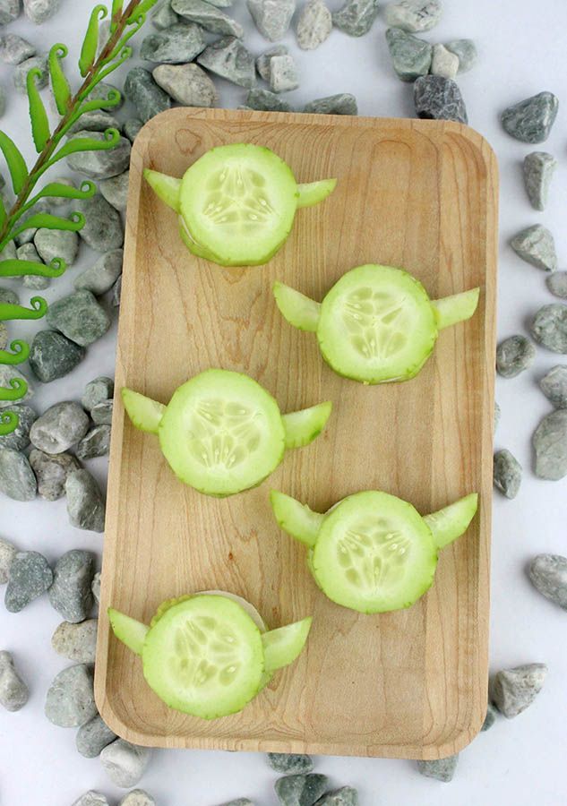 cucumbers cut into small pieces on a wooden cutting board next to rocks and leaves