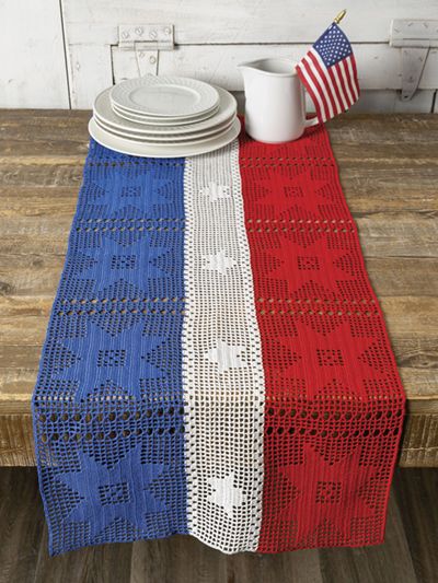 an american flag table runner on top of a wooden table with white plates and cups