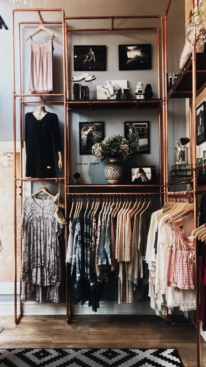 an open closet with clothes and pictures on the wall, next to a shelf full of clothing