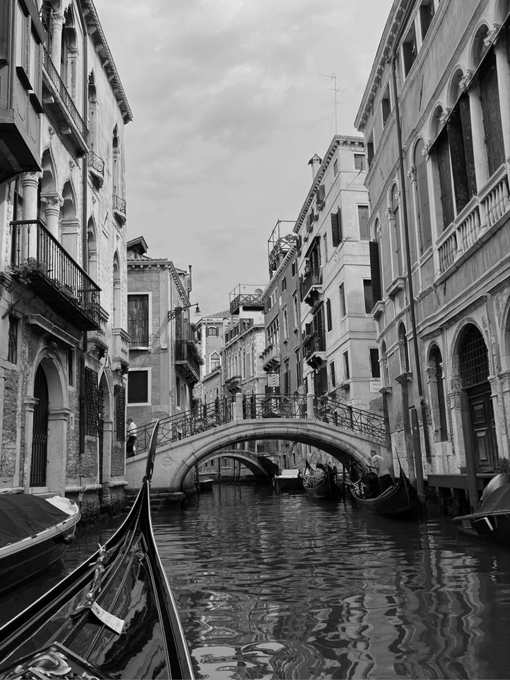 black and white photograph of a gondola passing under a bridge