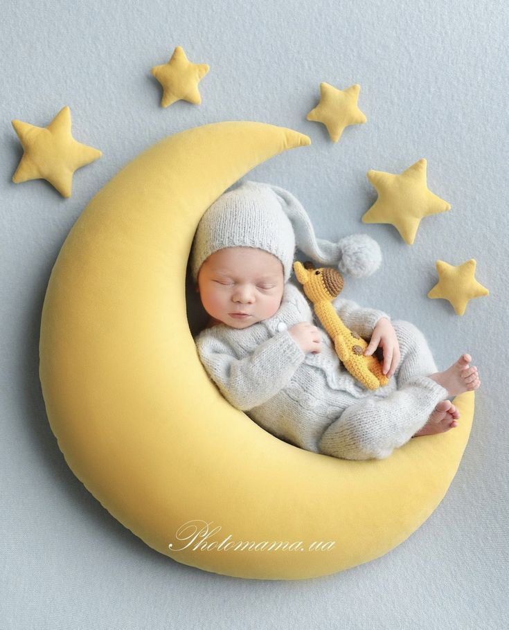 a baby is sleeping on the moon with a stuffed animal in it's lap