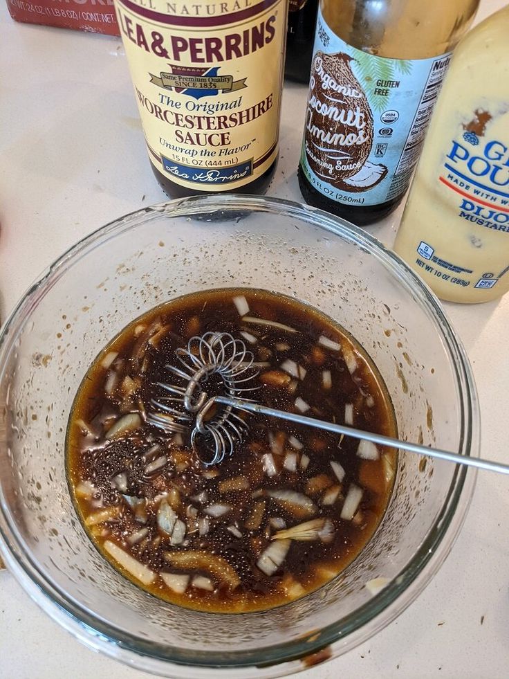 a bowl filled with food sitting on top of a table next to bottles of beer