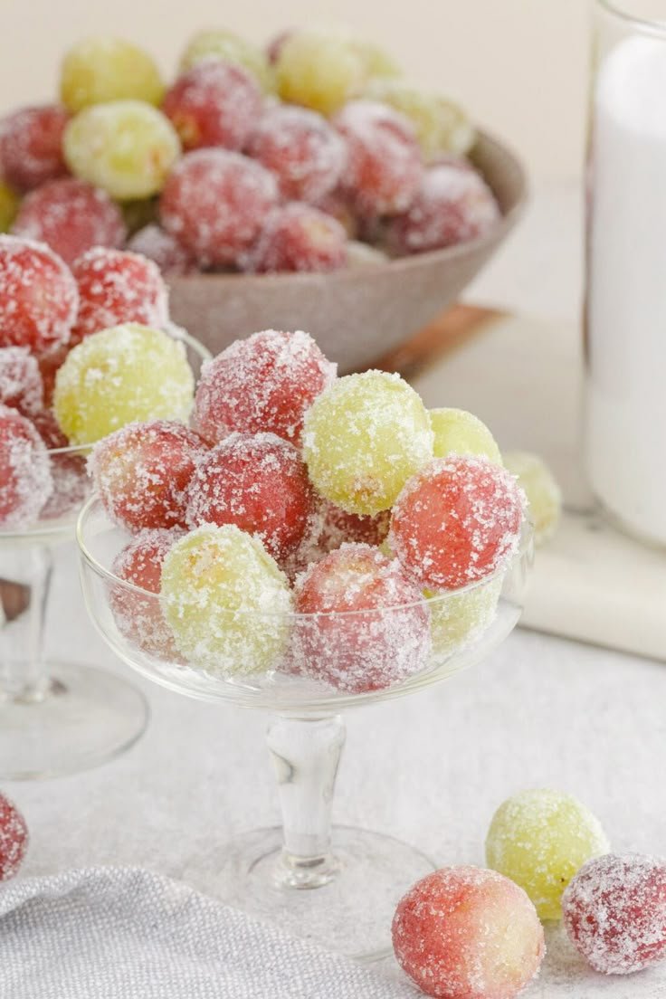 two glasses filled with sugar covered candies next to a bowl full of powdered sugar