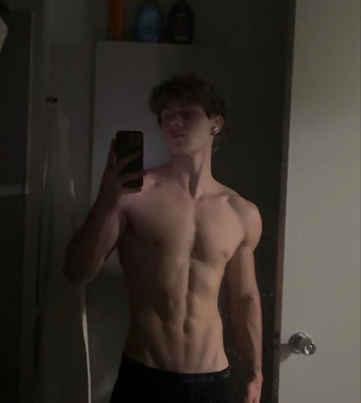 a shirtless man taking a selfie in the mirror