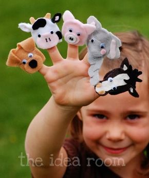 a young boy holding five finger puppets in front of his face with animals on them