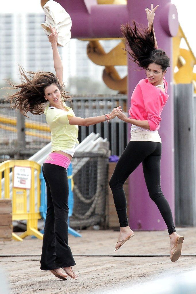 two girls jumping in the air with their arms outstretched