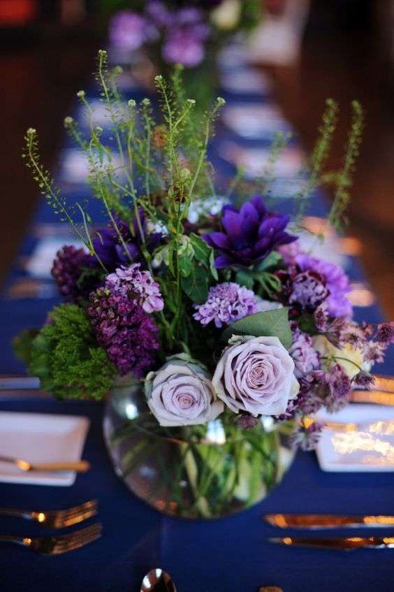 the table is set with purple flowers and silverware