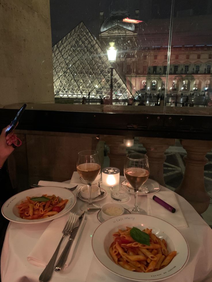 a table topped with plates of food and glasses of wine next to a tall pyramid