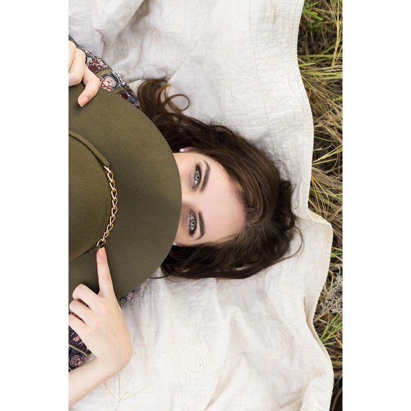 a woman laying in the grass with a hat on her head