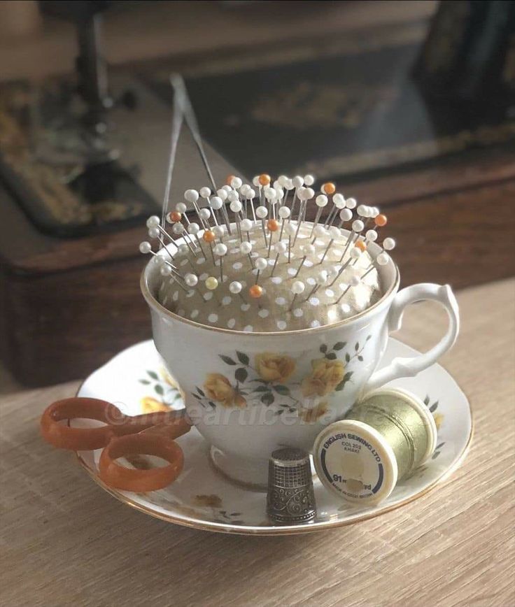 a teacup filled with pins sitting on top of a saucer