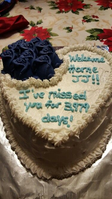 a heart shaped cake with blue frosting and flowers on the top is sitting on a table