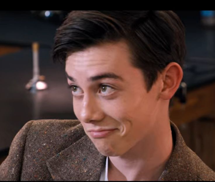 a close up of a person wearing a suit and tie with a smile on his face