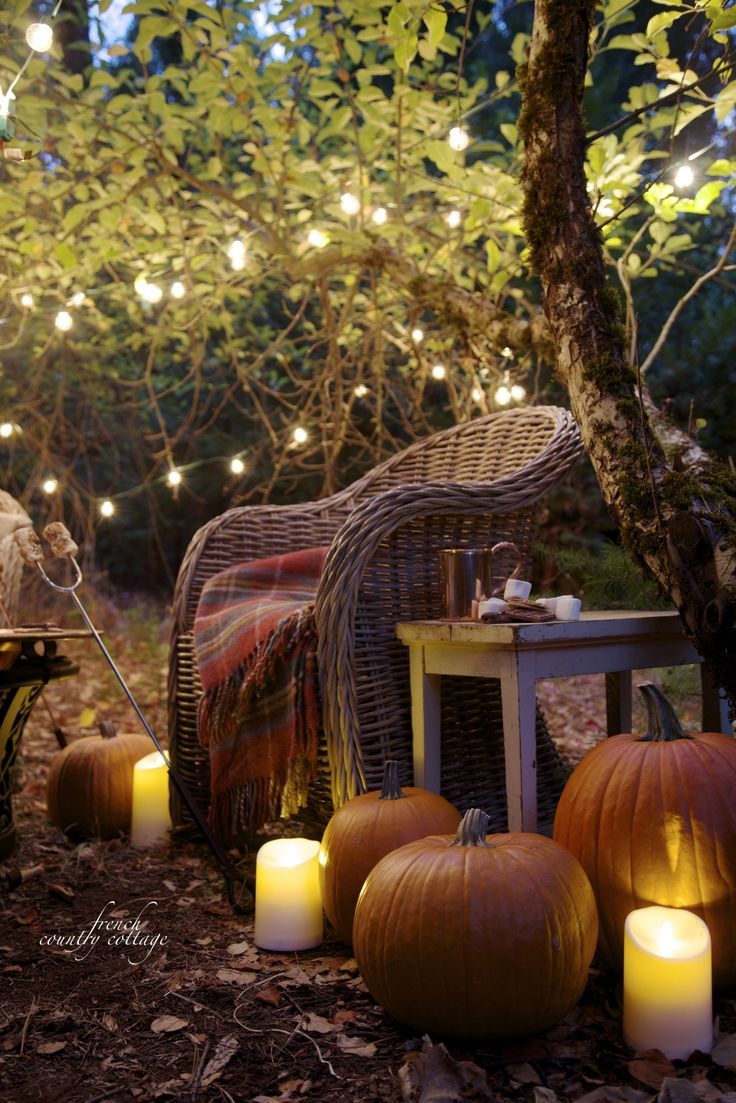 some pumpkins are sitting on the ground with candles in front of them and lights around them