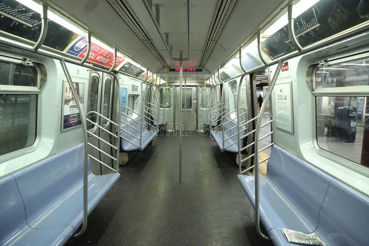 an empty subway car with blue seats and railings