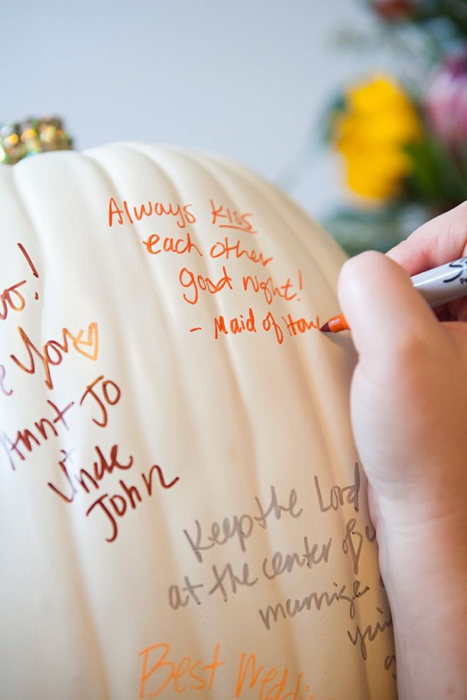 someone is writing on a pumpkin for their family