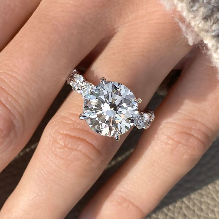 a woman's hand with a diamond ring on top of her finger and an engagement band