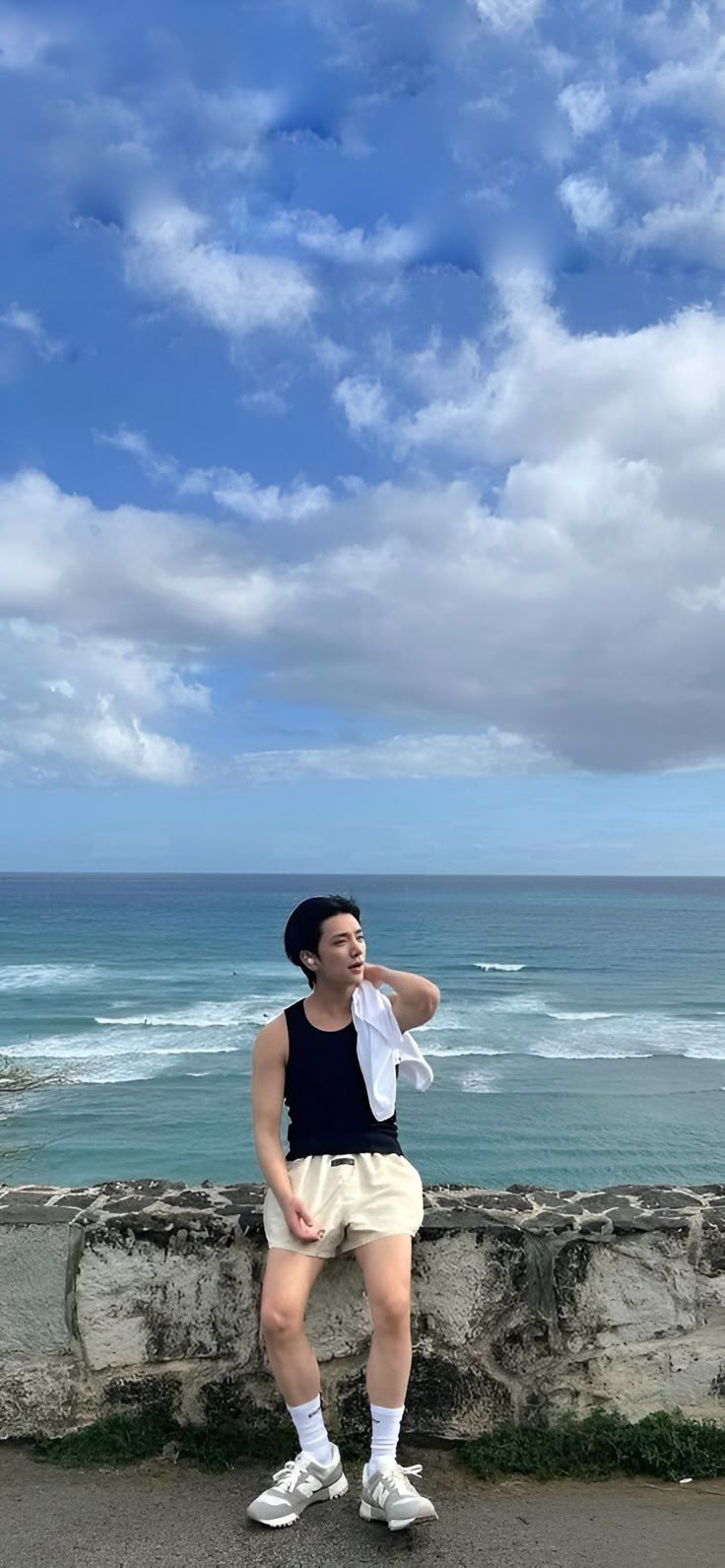 a man standing on the side of a road next to the ocean