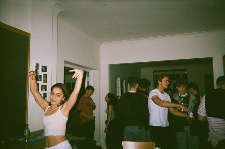 a group of people standing in a living room next to each other with arms up