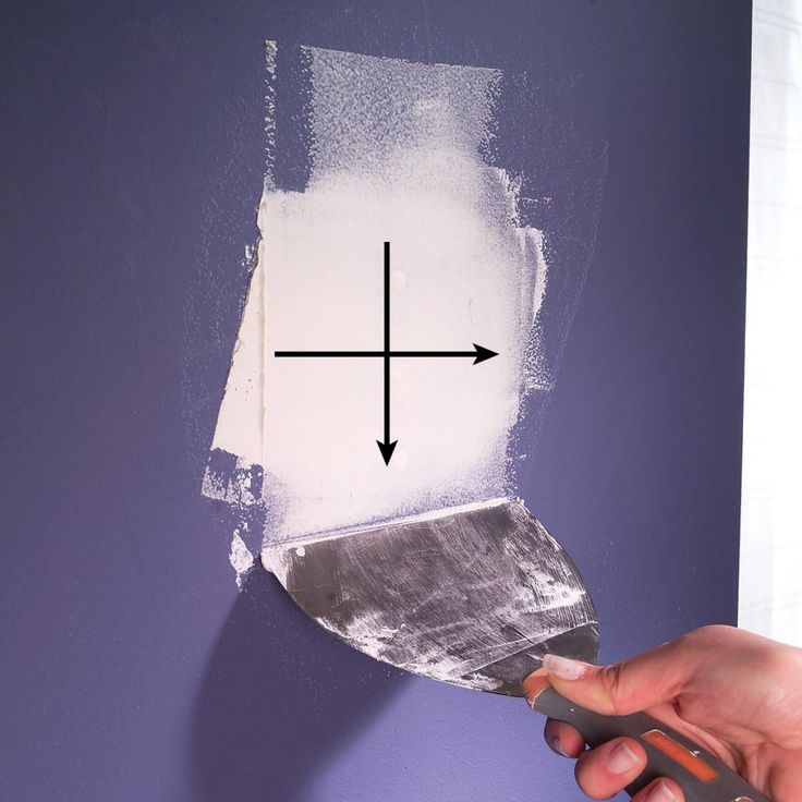 a person using a paint roller to paint a purple wall with an arrow pointing up