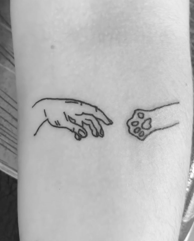 two hands touching each other with the creation of another hand tattoo on their left arm