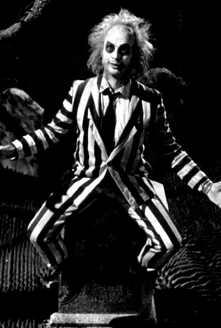 a man dressed in striped clothes and clown makeup