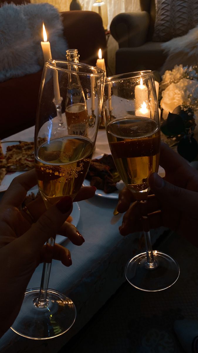 two people toasting wine glasses with candles in the background