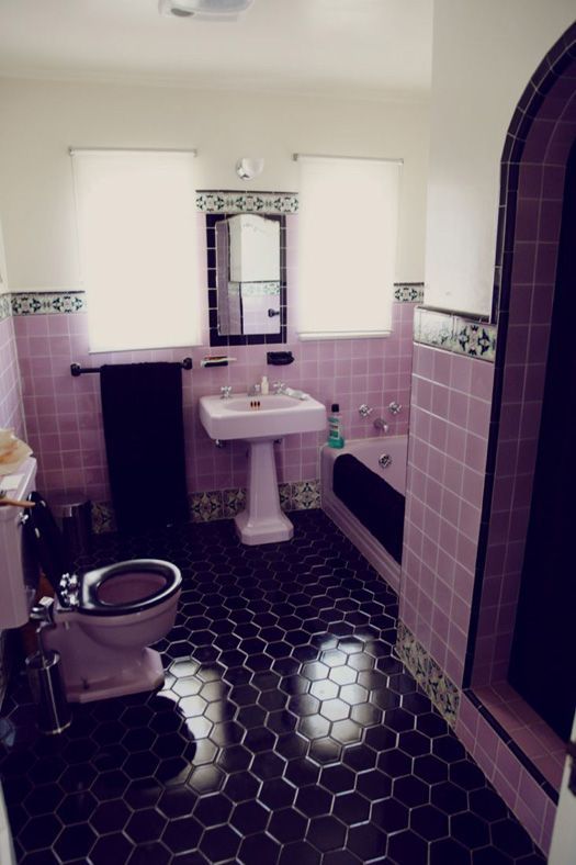 a bathroom with pink and black tiles on the floor