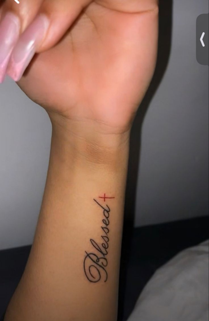 a woman's wrist tattoo with the words believe and cross on her left arm