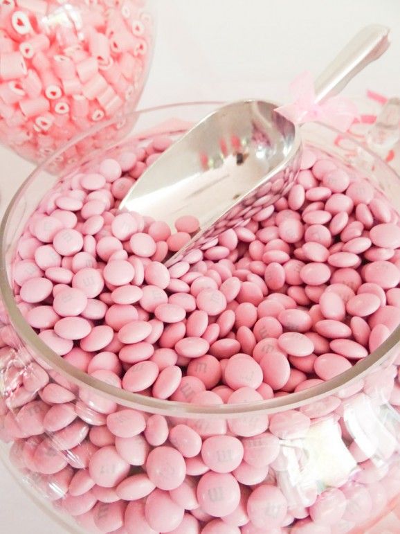 a bowl filled with pink candy beans and a spoon in it's centerpiece