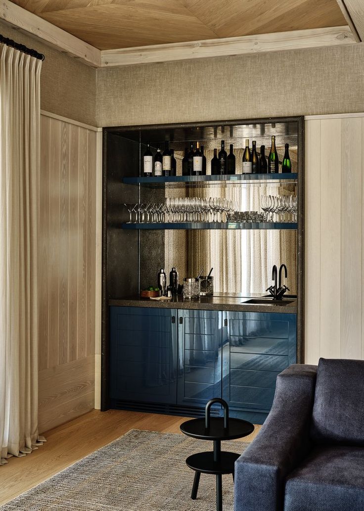 a living room filled with furniture and lots of bottles on top of the shelves next to a window