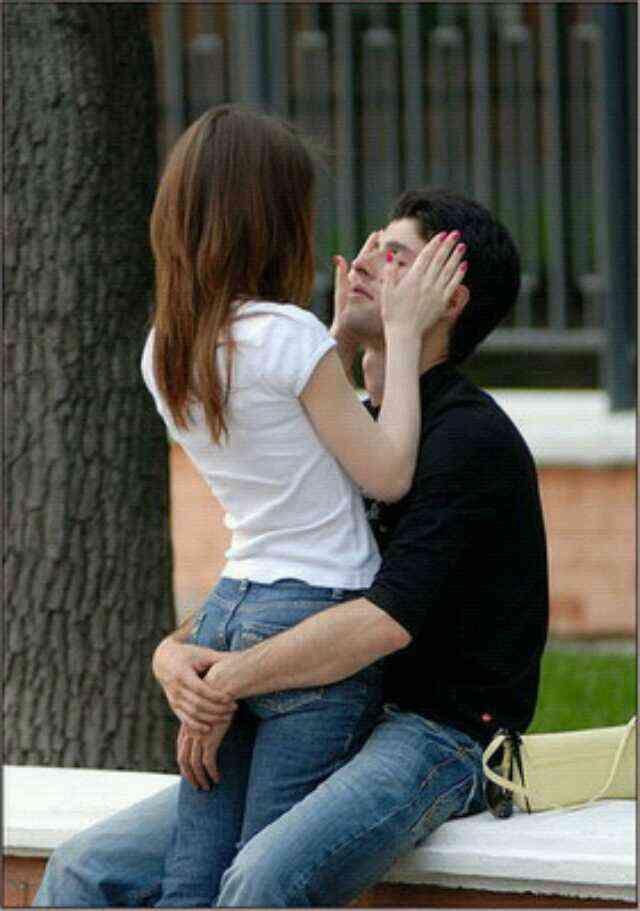 a man and woman sitting next to each other on a bench in front of a tree