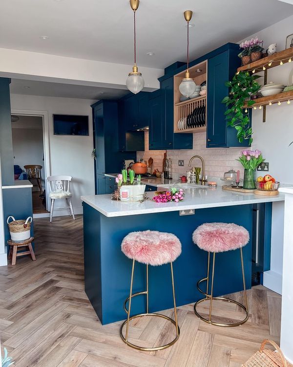 two stools are in front of an island with blue cabinets and white countertops