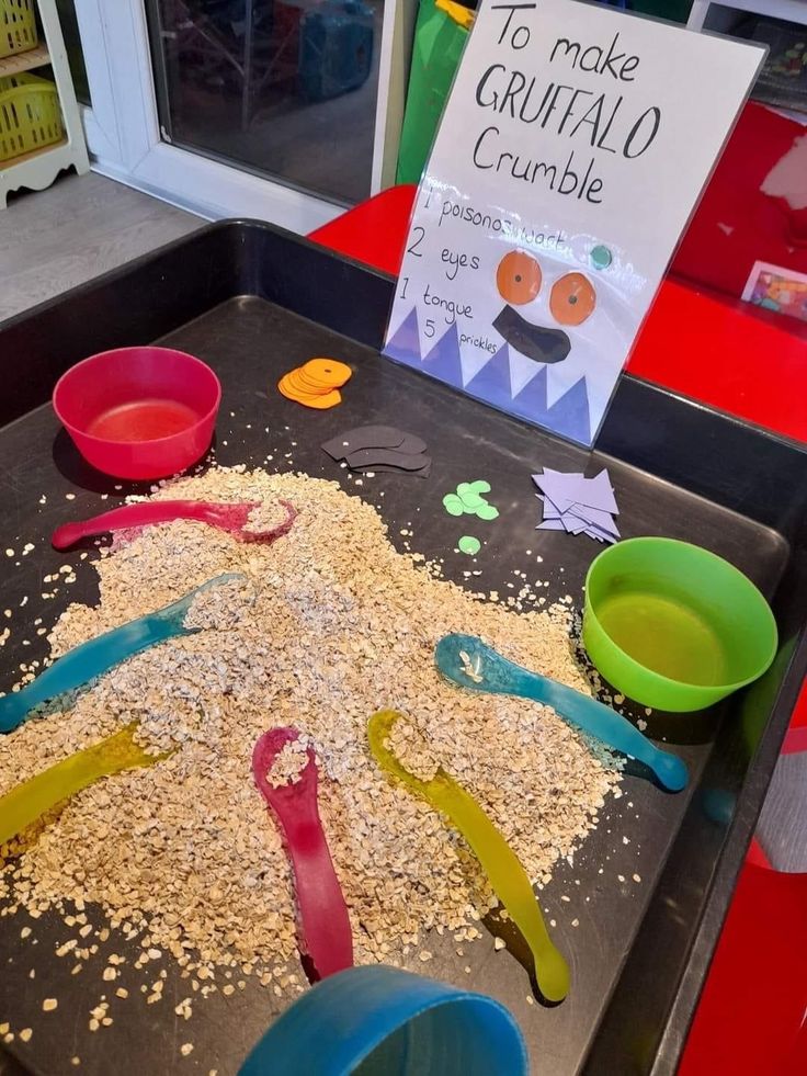 a child's play table with sand and plastic spoons