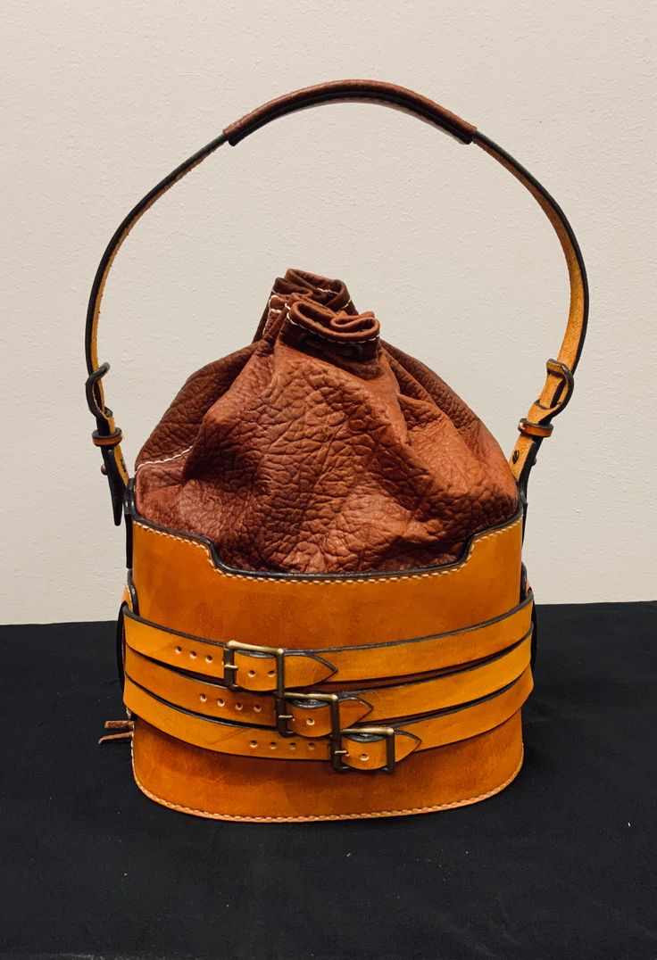 "Handmade leather bucket bag. Thick vegetable tan leather on lower half of bag and handle for durability and soft flexible leather on the top half for ease of use. Bag is closed with a draw string. All antique brass hardware. Hand stitched with 1mm woven thread. Height of bag (not including handle) = 13\" Oval shape bottom = 9 3/4\" x 7\"" Antique Brass Hardware, Top Handle Bags, Leather Bucket Bag, Leather Bucket, Brass Hardware, Handmade Leather, Hand Stitched, Leather Handmade, Tan Leather