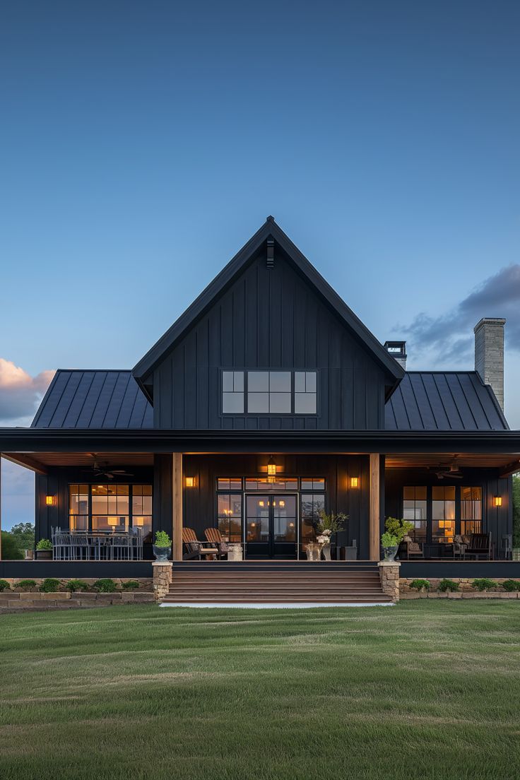 a large black house with lots of windows on the front and side of it at dusk