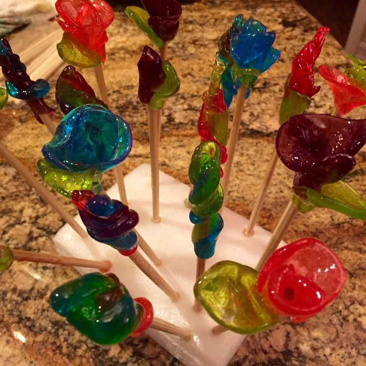 several colorful lollipops are sitting on a marble counter top in the shape of flowers