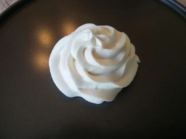 a cupcake with white frosting sitting on top of a black plate