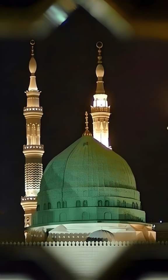 a large green dome on top of a tall building at night with street lights in the background