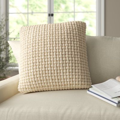 a white pillow sitting on top of a couch next to a book