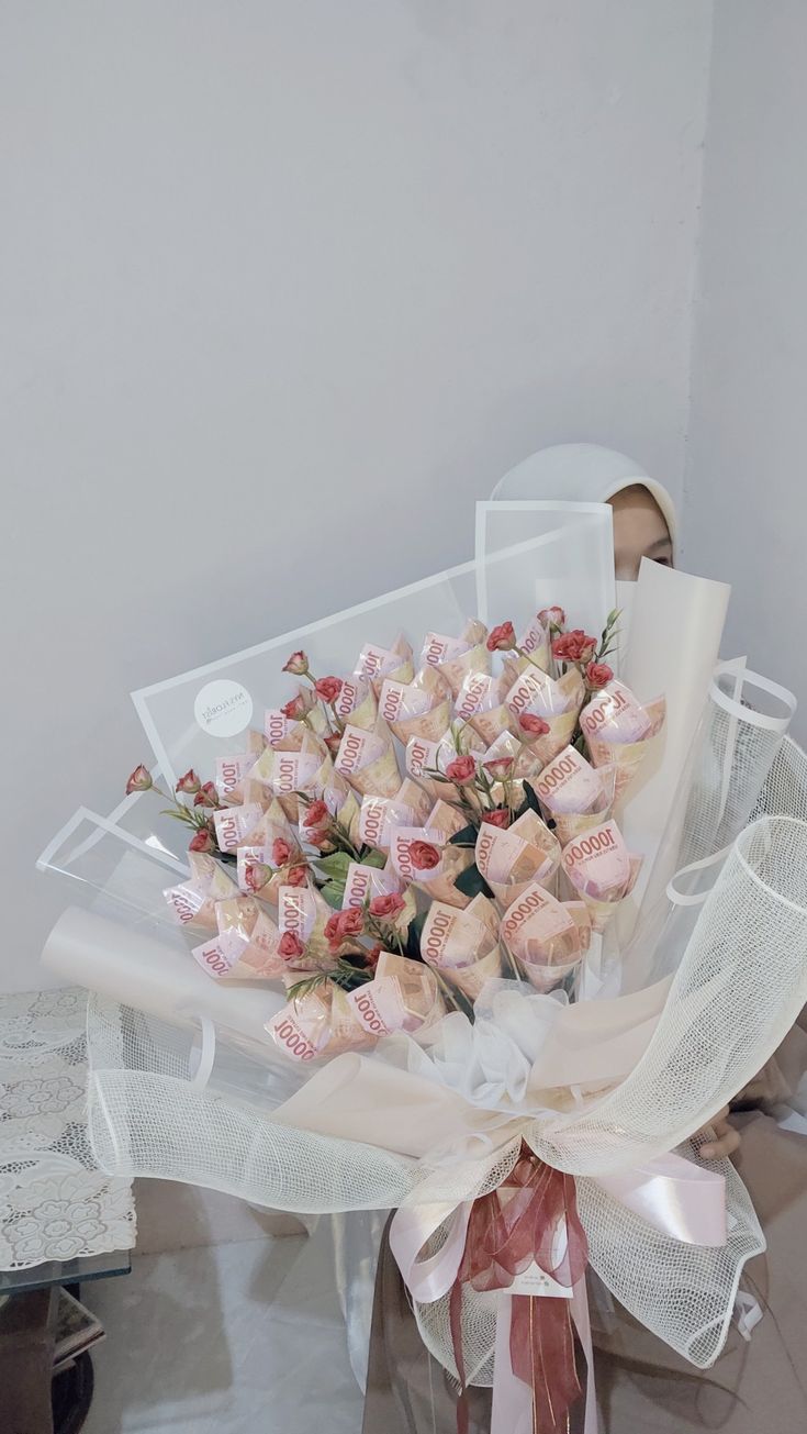 a bouquet of pink roses wrapped in organe and tied to a white ribbon on top of a table