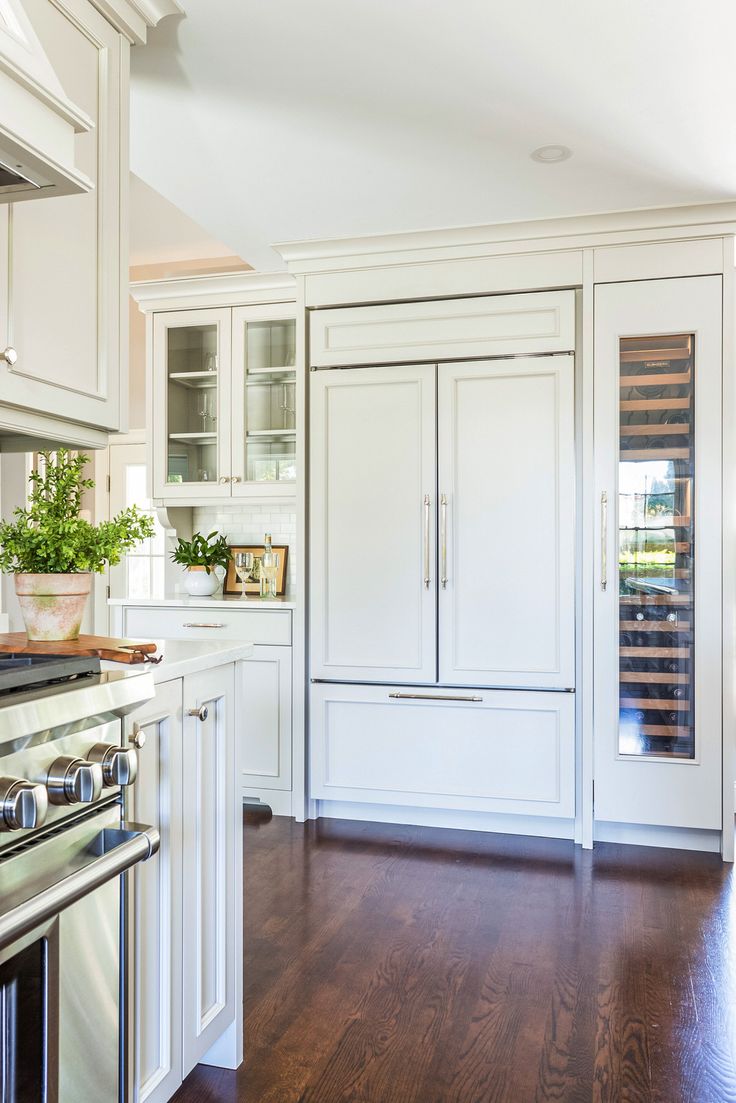 a kitchen with white cabinets and wood flooring, including an oven in the center