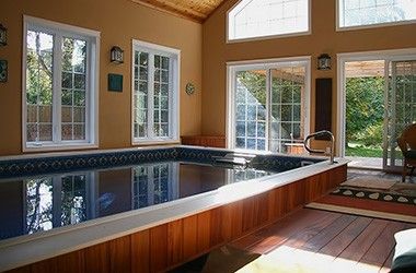 a large indoor swimming pool in the middle of a living room with sliding glass doors