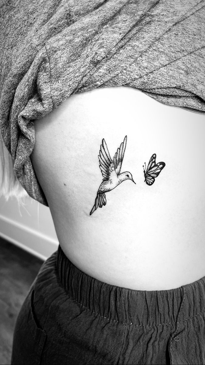 a black and white photo of a woman's stomach with two birds on it