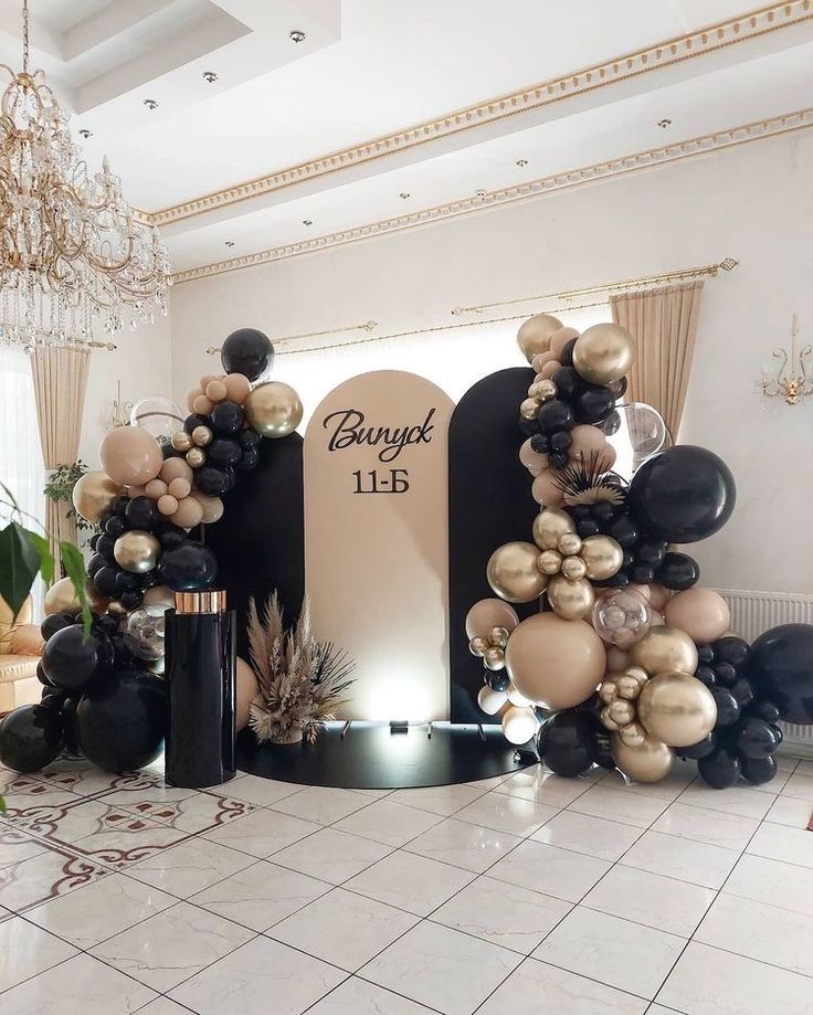 an entrance decorated with black, gold and white balloons