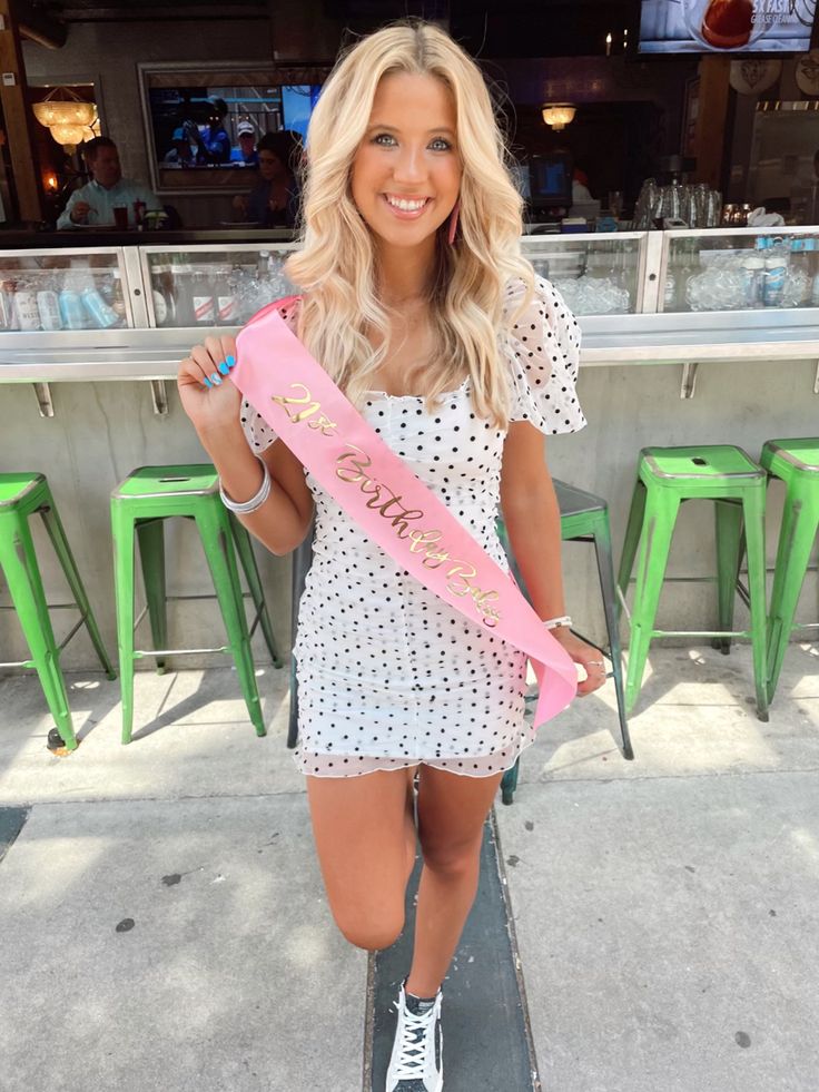 a woman standing on top of a skateboard holding a pink sash