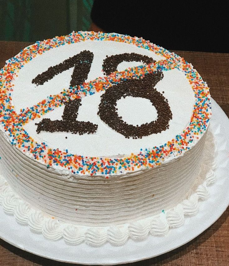 a white cake with sprinkles and the number twenty six is on a plate