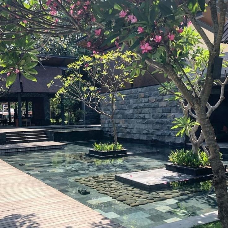 an outdoor area with water and trees in the center, surrounded by stone steps leading up to a building